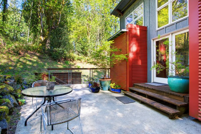 small concrete patio decorated with plants and a dinning area
